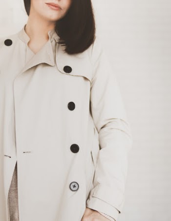 Woman Wearing Beige Coat in Front White Wall