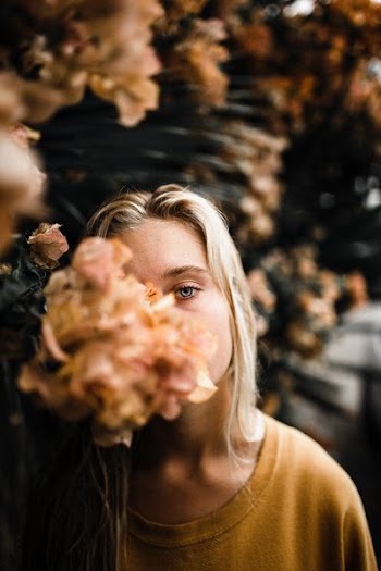 woman wearing beige top beside brown flowers during daytime