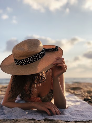 Woman Wearing Bikini Top And Brown Hat Sunbathing On The Beach 