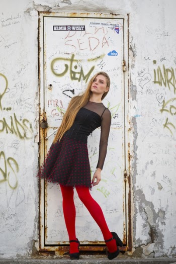 Woman Wearing Black and Red Long-sleeved Mini Dress and Red Leggings in Front of a Closed White Metal Door