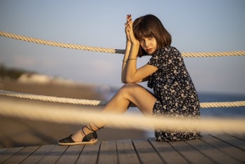 Woman Wearing Black and White Floral Dress Sitting on Boardwalk