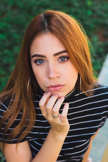 Woman Wearing Black and White Striped Shirt Putting Finger on Her Chin