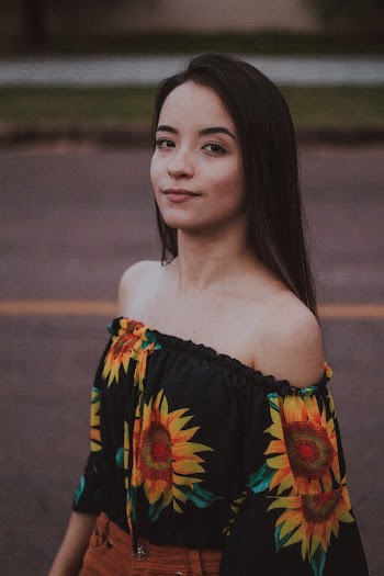 Woman Wearing Black and Yellow Sunflower Printed Off-shoulder Blouse Brown Denim Bottom