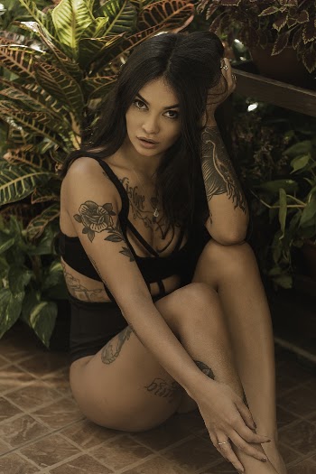 Woman Wearing Black Bikini While Sitting Near Plants