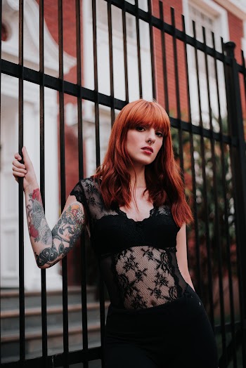 Woman Wearing Black Cap Sleeve Top Beside Black Metal Gate