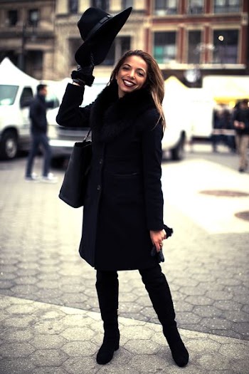 woman wearing black coat standing on gray concrete pavement