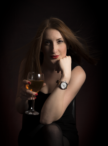 Woman Wearing Black Dress Holding Clear Wine Glass in Dark Room