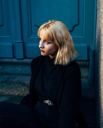 Woman Wearing Black Dress Sitting Beside Door