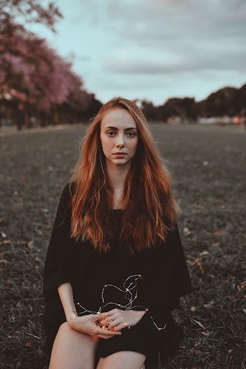 Woman Wearing Black Dress Sitting on Grass Field