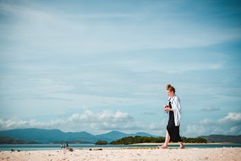 Woman Wearing Black Dress Walking on Seashore