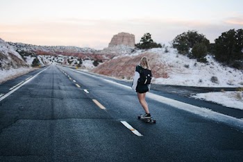 woman wearing black jacket and shorts walking on asphalt road