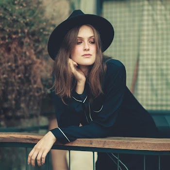 Woman Wearing Black Jacket Leaning on Wooden Railings