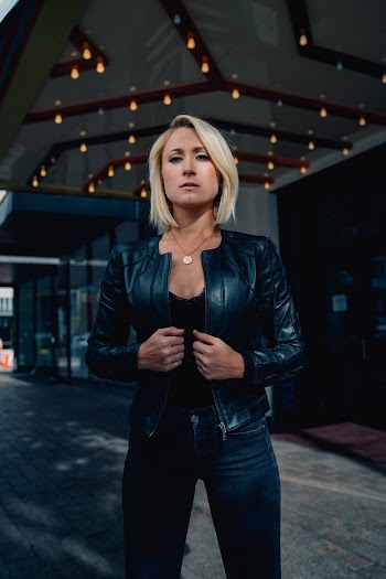 Woman Wearing Black Leather Jacket and Blue Denim Fitted Jeans
