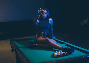 Woman Wearing Black Leather Mini Skirt Sitting on Billiard Table