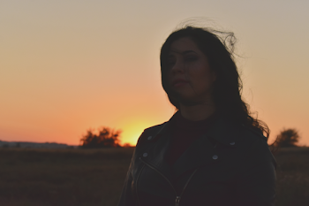 Woman Wearing Black Leather Zip-up Jacket Standing on Field during Golden Hour