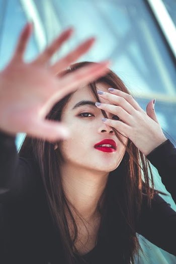woman wearing black long-sleeved shirt with gray manicure covering her eye