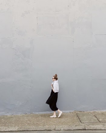 Woman Wearing Black Maxi Dress and Pair of White Flats Standing Beside Gray Wall