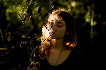 woman wearing black necklace smelling plant during daytime
