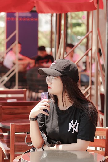 Woman Wearing Black New York Yankees Crew-neck Shirt and Black Fitted Cap Holding Phone