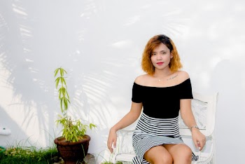 Woman Wearing Black off shoulder Top and Striped Skirt Sitting on White Armchair