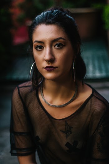 Woman Wearing Black See Through Blouse and Silver-colored Hoop Earrings Looking Straight