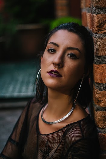Woman Wearing Black Sheer Top Leaning on Brown Bricked Wall
