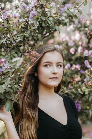 woman wearing black shirt beside purple petaled flowers