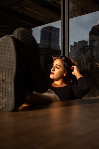 Woman Wearing Black Shirt Sitting on Beside Table