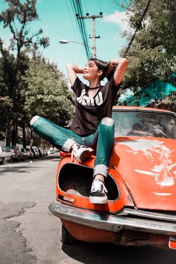 woman wearing black shirt sitting on orange vehicle