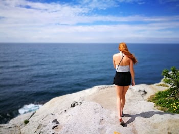 Woman Wearing Black Skirt Walking on Side of Cliff