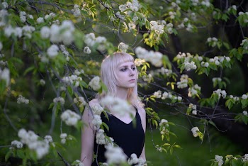 Woman Wearing Black Sleeveless V-neck Top Standing Between White Petaled Flowers