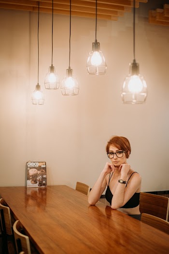 Woman Wearing Black Spaghetti Strap Crop Top Sitting by the Table Inside Room