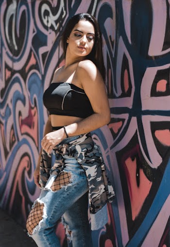 Woman Wearing Black Sports Bra Leaning on White and Blue Painted Wall