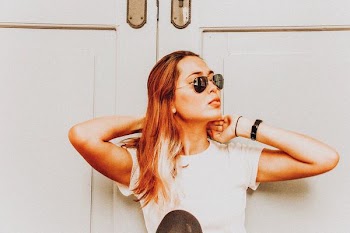 woman wearing black sunglasses standing in front of door at daytime