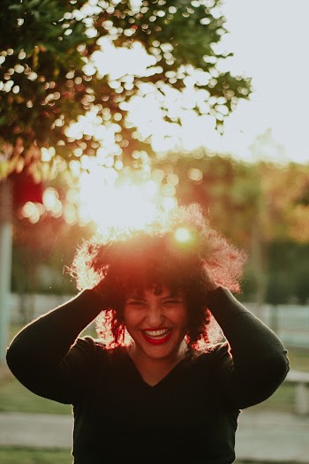 Woman Wearing Black Sweater Holding Her Hair While Smiling