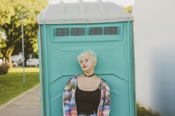 Woman Wearing Black Tank Top Leaning on Teal Booth