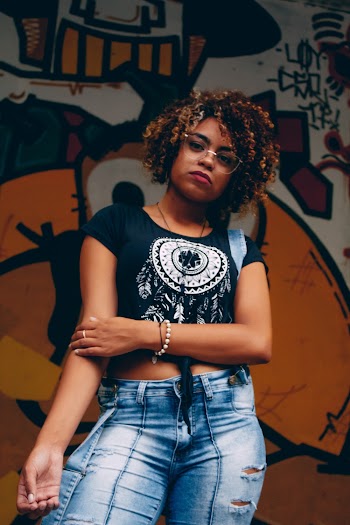 Woman Wearing Black Top and Blue Denim Bottoms Standing Front of Graffiti Wall