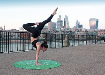 Woman Wearing Black Top And Leggings On Green Yoga Mat