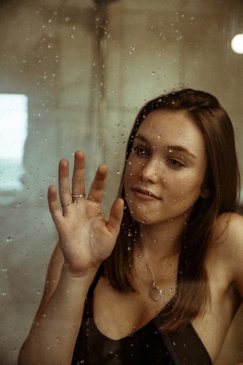 Woman Wearing Black Top Holding on Glass Panel