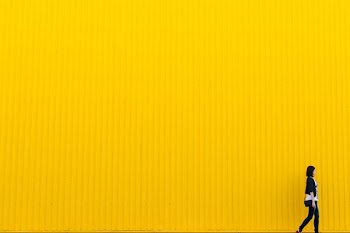 woman wearing black top standing near yellow wall