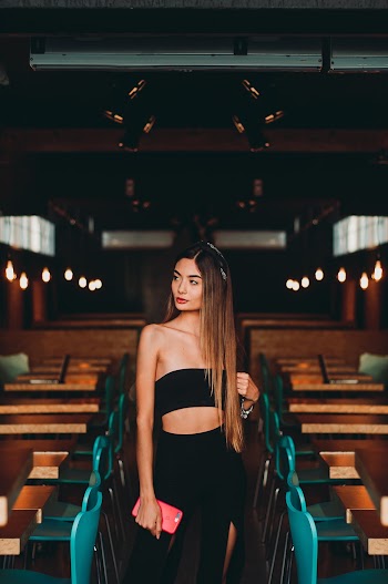 Woman Wearing Black Tube Top Standing In Between Tables and Chairs 