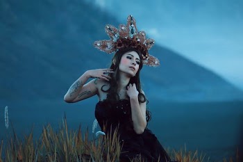 woman wearing black tube top with brown and white headdress standing in field