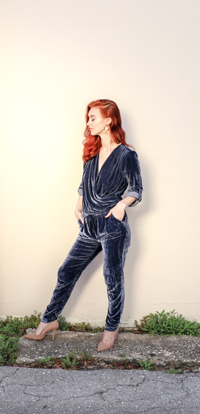 Woman Wearing Black Velvet Surplice Jumpsuit Standing Beside Wall