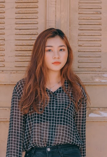 Woman Wearing Blouse and Denim Bottoms Standing Against the Wall