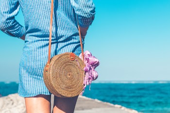 Woman Wearing Blue and White Striped Dress With Brown Rattan Crossbody Bag Near Ocean