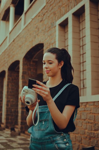 Woman Wearing Blue Denim Dungarees Holding White Camera