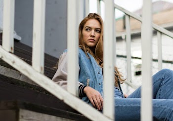 Woman Wearing Blue Denim Jacket and Blue Denim Jeans Sitting on Staircase