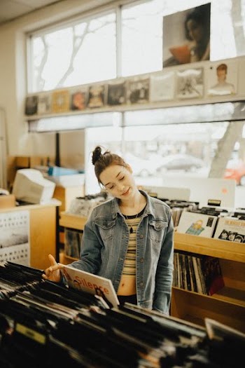 woman wearing blue denim jacket holding book
