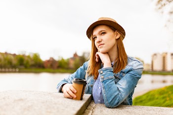 Woman Wearing Blue Denim Jacket Holding Coffee Cup Standing Near Concrete Platform