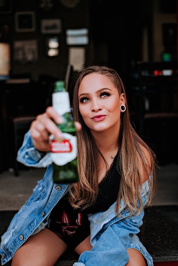 Woman Wearing Blue Denim Jacket Holding White Labeled Bottle